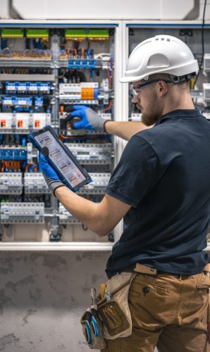 Electrical technician working in a switchboard with fuses, uses a tablet. Electrical technician looking focused while working in a switchboard with fuses. SSUCv3H4sIAAAAAAAACpySwW6DMAyG75P2DijnIgGBju5Vqh1MSMFqmlRJ6DRVffc5CaDsOnHBn+3f/jHP97eiYAM4FOyzeIaIYlRqcd6CR6MJV4eVW6lHaXPysPxY5QAwj+SI3lgElcMBvJg13CRBvSgV8CsmmfPgFydd2GVFArycSCPBXSItfE5xsSVikjooxdghY24ZIttQEv9XZ3r52g1PUoufuHBmxEolIRk5p1J2/fbS3nJrsIxoMlcPI0CFAp4pAd7Bwp++u0WBesqI8XO8y6YkzKK9DVvtZpgy5g6DCl/9QmPkxmdwjsrHjWezBf0F5pbN0cZHT6sqG+k4Iaw5747NBz193fZN1ZzWgnTQGUknrrMJUSyuOOauMGxAJzi1XVdBCU3Ly7aq67Lvu65seNe3cOLHgV/oFq9fAAAA//8DAIlQOhS5AgAA