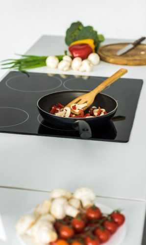 frying pan with vegetables on electric stove in kitchen