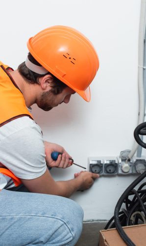 Side view of workman holding screwdriver near sockets